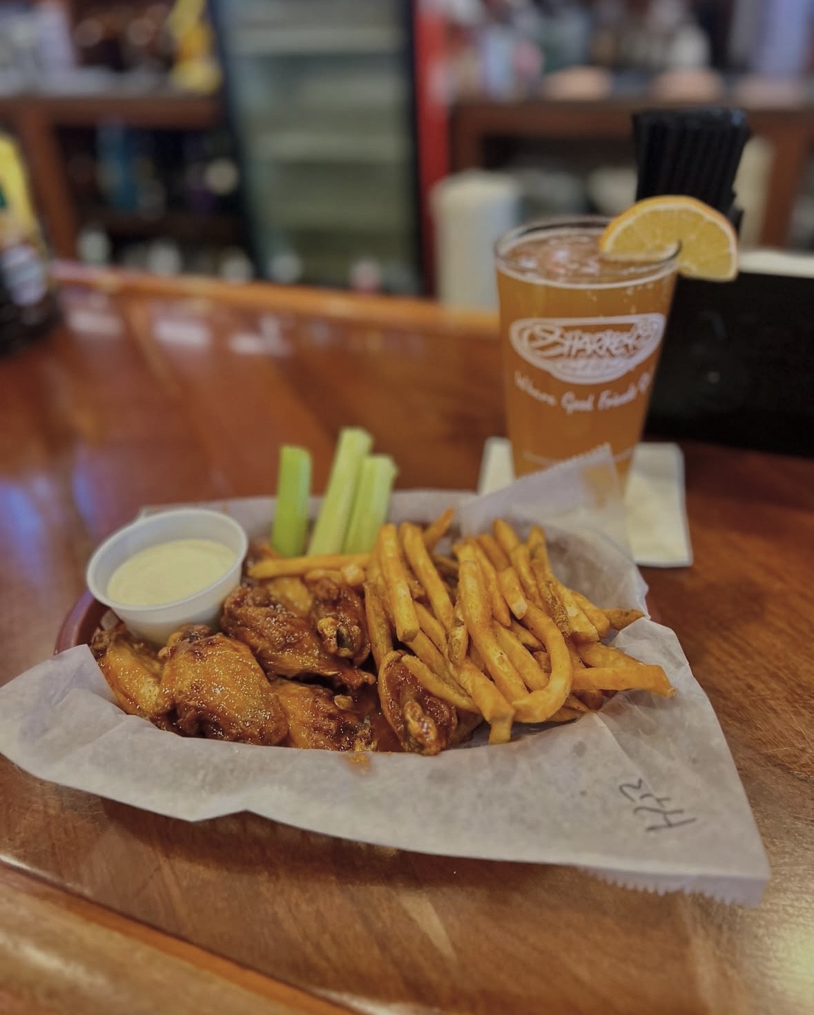 a plate of chicken wings and fries with sauces and a drink