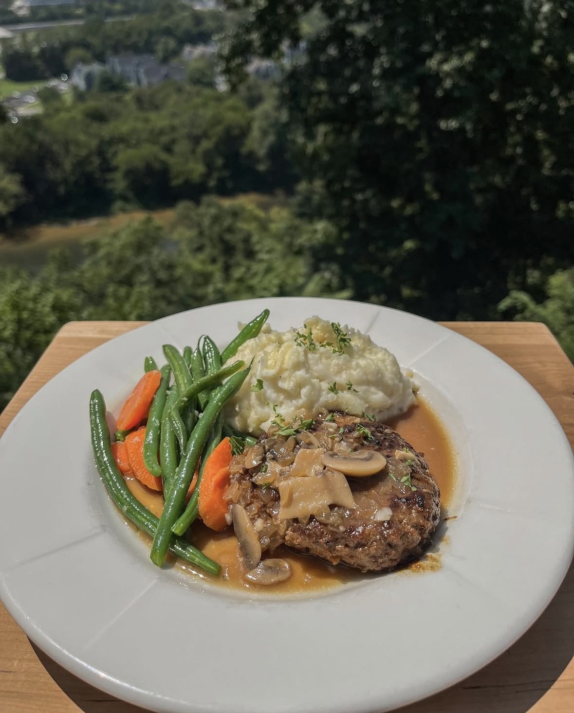 a plate of food with a view of trees and a river