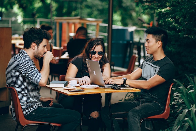 a group of people sitting at a table with a laptop